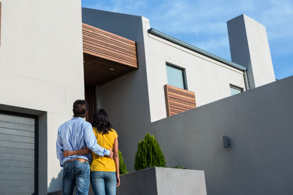 Young couple contemplating their new house from the outside - How to Improve Cash Flow on Rental Properties - DG Pinnacle Commercial Loans - Miami Mortgage Lender