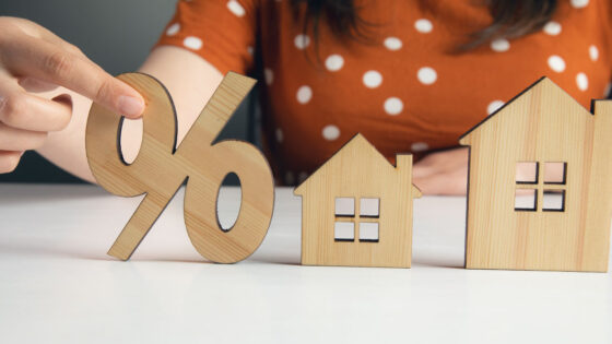 Female holding home model and wooden sale percentage sign - Benefits of Soft Money Loans for Investment Properties - DG Pinnacle Commercial - Miami Mortgage Lender