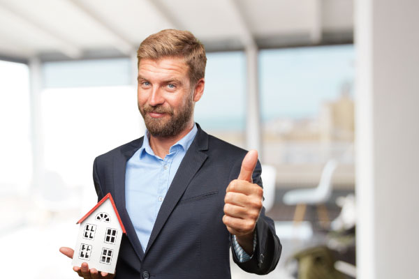 Happy Businessman thumbs up while holding model house | What are the Benefits of a DSCR Loan? | DG Pinnacle Commercial - Miami Mortgage Lender