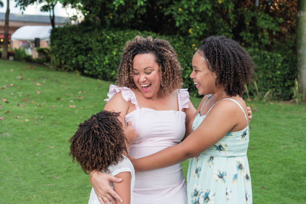 Latin Mom smiling next to her daughters in a garden | Mortgage Loans For Foreign Nationals Customers | DG Pinnacle Commercial - Miami Mortgage Lender