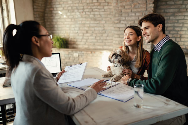 Female mortgage officer at office talking to a couple with a puppy - 5 Mortgage Lending Strategies to Help Your Customers | DG Pinnacle Commercial | Miami Wholesale Mortgage Funding Lender