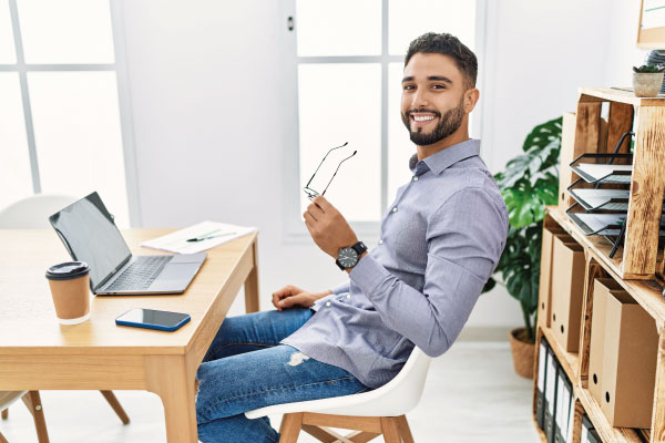 Happy young man in from of his desktop | No Income Verification Mortgage Loans For Your Customers | DG Pinnacle Commercial - Miami Mortgage Lender